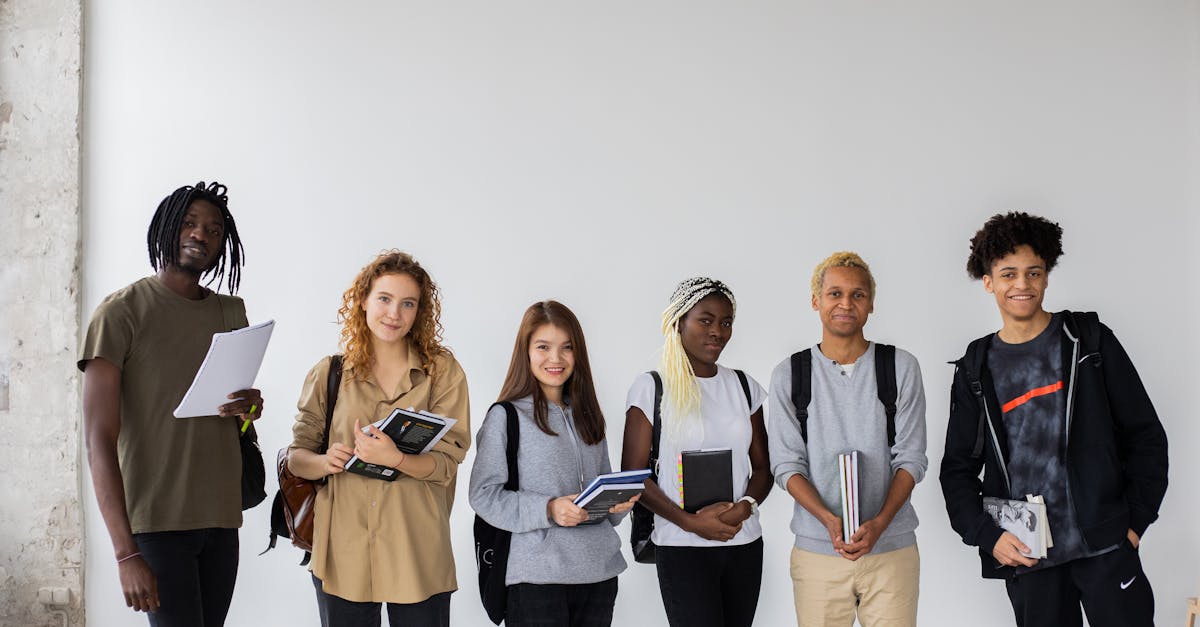 Group of diverse young multiracial classmates with notebooks and textbooks and backpacks smiling at camera